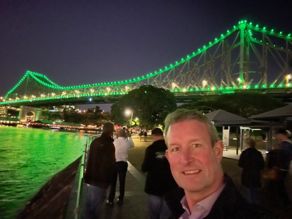 Chris Thomas with the Story Bridge beyond lit in green for World Ranger Day.